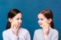 Two girls wash themselves with face sponges, smile and look at each other on a blue background. Child Hygiene Concept