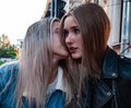 Two girls whisper while sitting at the table. Royalty Free Stock Photo