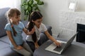 Two girls working on laptop, smiling and older sister help younger Royalty Free Stock Photo