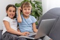 Two girls working on laptop, smiling and older sister help younger Royalty Free Stock Photo