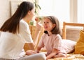 Two girls, younger and older happy sisters enjoying time together, playing and having fun while sitting on the bed in pajamas Royalty Free Stock Photo