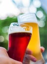 Two glass of beer in hand. Beer glasses clinking at outdoor bar or pub Royalty Free Stock Photo