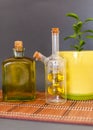 Two glass bottles olive oil stands near a flower against a dark background.