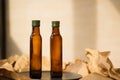 Two glass brown transparent faceted bottles empty and full with vegetable oil stands on a black plate on paper. Salad dressing. Royalty Free Stock Photo