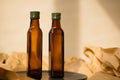 Two glass brown transparent faceted bottles without labels empty and full with vegetable oil with green metal caps Royalty Free Stock Photo