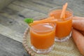 Two glass of carrot juice on wicker basket on wooden background