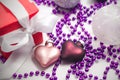 Two glass Christmas decorations in the shape of a heart of pink and purple, a red gift box with a white ribbon Royalty Free Stock Photo