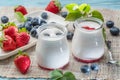 Two glass containers with plain yoghurt and berries on the table. Light summer mood