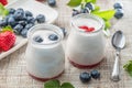 Two glass containers with plain yoghurt and berries on the table. Light summer mood