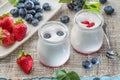 Two glass containers with plain yoghurt and berries on the table. Light summer mood