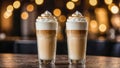 Two glass cup of coffee latte macchiato with cinnamon-sprinkled foam on the table in the cafe. Blurred background