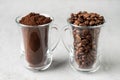 Two glass cups with coffee beans and ground coffee on light concrete background Royalty Free Stock Photo
