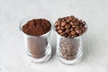 Two glass cups with coffee beans and ground coffee on light concrete background Royalty Free Stock Photo