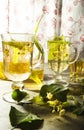 Two glass cups of freshly made yellow linden tea with leaves and flowers of linden tree Royalty Free Stock Photo