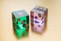 Two glass dice, green and pink, on a gold background in sunlight. Result one and six. Royalty Free Stock Photo
