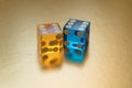 Two glass dice, yellow and blue, on a gold background in sunlight. The result is six and six.
