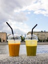 Two glass of fresh smoothie on city embankment - mango and banan