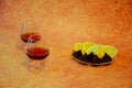 Two glass glasses with cognac and a plate with chocolate candies and cut lemon on a brown abstract background Royalty Free Stock Photo