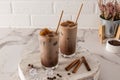 Two glass glasses with cold latte coffee or with a chocolate drink and ice cubes, cinnamon on a wooden white board and a marble Royalty Free Stock Photo