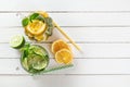 Two glass glasses with homemade lemonade from lime and lemon, cocktail tubes, sliced citrus and mint on a white wood Royalty Free Stock Photo