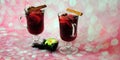 Two glass glasses of hot wine with apple, orange slices, pine needles and a flower stand on a pink abstract background with Royalty Free Stock Photo