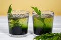 Two glass with Green Chlorophyll on white table, Orange Background. Antioxidant drinks, Superfood, Aragula