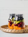 Two glass jars with berries and fruits. Fruit salad with apricots, kiwi, cherries and blueberries in glass jars on white Royalty Free Stock Photo