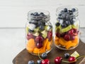 Two glass jars with berries and fruits. Fruit salad with apricots, kiwi, cherries and blueberries in glass jars on white Royalty Free Stock Photo