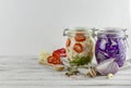 Two glass jars of fermented red cabbage, cauliflower. vegetables on a light background, using textile light gray. fermentation is