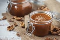 Two glass jars of homemade caramel with crystals of salt, nutshells and star anise Royalty Free Stock Photo