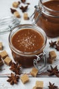 Two glass jars of homemade caramel with crystals of salt, pieces of cane sugar and star anise Royalty Free Stock Photo