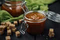 Two glass jars with homemade salted caramel and pieces of brown sugar with salt crystals on green gauze Royalty Free Stock Photo