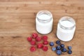 Two glass jars with yogurt, raspberries and blueberries horizontal. Royalty Free Stock Photo