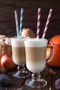 Two glass latte mugs stand on a wooden table. Coffee and milk are poured in layers, tubes with stripes are inserted on top of the Royalty Free Stock Photo