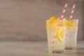 Two glass of lemonade with lemons and lime and straw, on a dark background, with space, a cool drink and summer mood