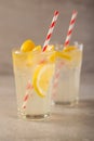 Two glass of lemonade with lemons and lime and straw, on a dark background, with space, a cool drink and summer mood