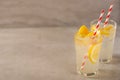 Two glass of lemonade with lemons and lime and straw, on a dark background, with space, a cool drink and summer mood