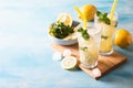 Two glass with lemonade or mojito cocktail with lemon and mint, cold refreshing drink or beverage with ice on blue background. Royalty Free Stock Photo