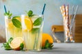 Two glass with lemonade or mojito cocktail with lemon and mint, cold refreshing drink or beverage with ice on rustic blue Royalty Free Stock Photo