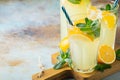 Two glass with lemonade or mojito cocktail with lemon and mint, cold refreshing drink or beverage with ice on rustic blue Royalty Free Stock Photo