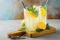 Two glass with lemonade or mojito cocktail with lemon and mint, cold refreshing drink or beverage with ice on rustic blue Royalty Free Stock Photo