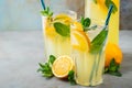 Two glass with lemonade or mojito cocktail with lemon and mint, cold refreshing drink or beverage with ice on rustic blue Royalty Free Stock Photo