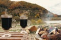 Two glass with mulled red wine on autumn mountains background. Picnic with alcohol drinks and campfire. Royalty Free Stock Photo