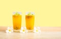 Two glass of passionfruit juice with mint and flowers on wooden table, isolated on pastel yellow background, die cut with clipping