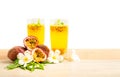 Two glass of passionfruit juice with mint and group of purple skin passionfruit plant, sliced and round fruits on wooden table