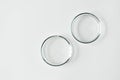 Two glass petri dish with transparent gel with air bubbles and one empty on white background, top view and copy space Royalty Free Stock Photo