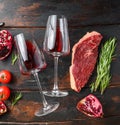 Two glass of red wine near raw beef steak over old dark wooden table top view. Big size Royalty Free Stock Photo