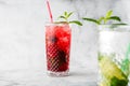 Two glass with strawberry and classic mojito cocktail with lemon and mint, cold refreshing drink or beverage with ice on bright Royalty Free Stock Photo