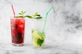 Two glass with strawberry and classic mojito cocktail with lemon and mint, cold refreshing drink or beverage with ice on bright Royalty Free Stock Photo