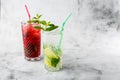 Two glass with strawberry and classic mojito cocktail with lemon and mint, cold refreshing drink or beverage with ice on bright